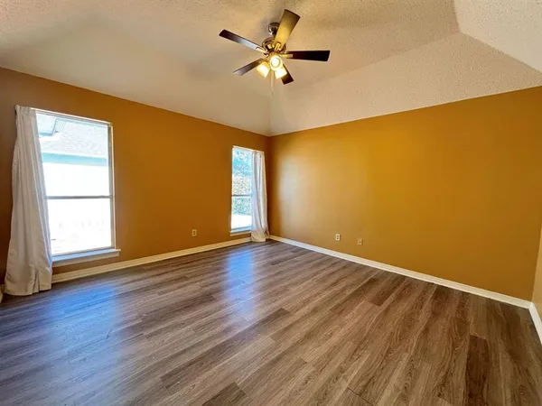 a view of an empty room with window and wooden floor