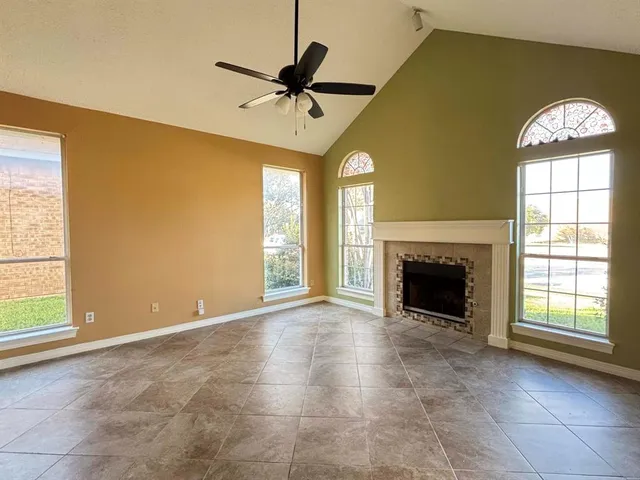 an empty room with windows and fireplace
