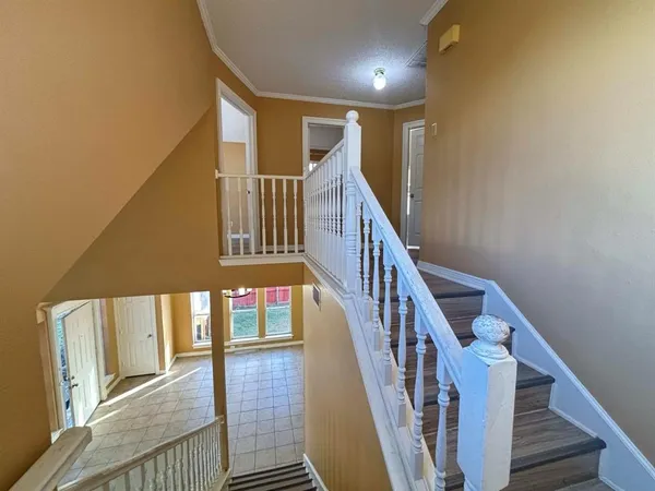 a view of staircase with lots of frames on wall and wooden floor