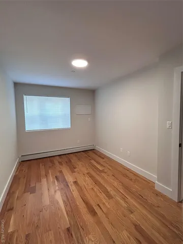 a view of an empty room and wooden floor and window