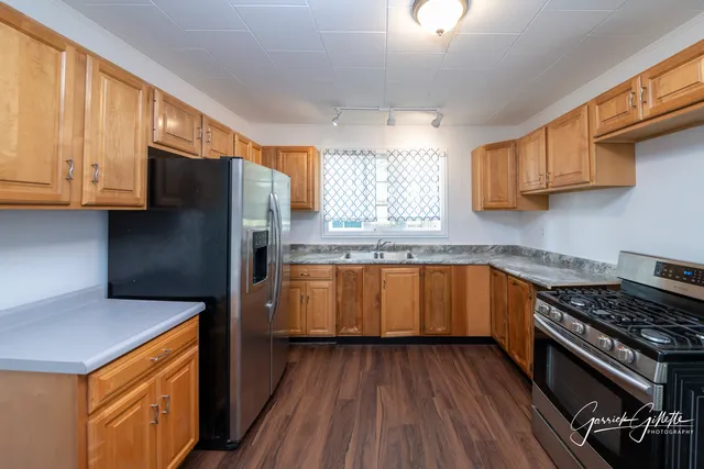 a kitchen with granite countertop wooden floors wooden cabinets and stainless steel appliances