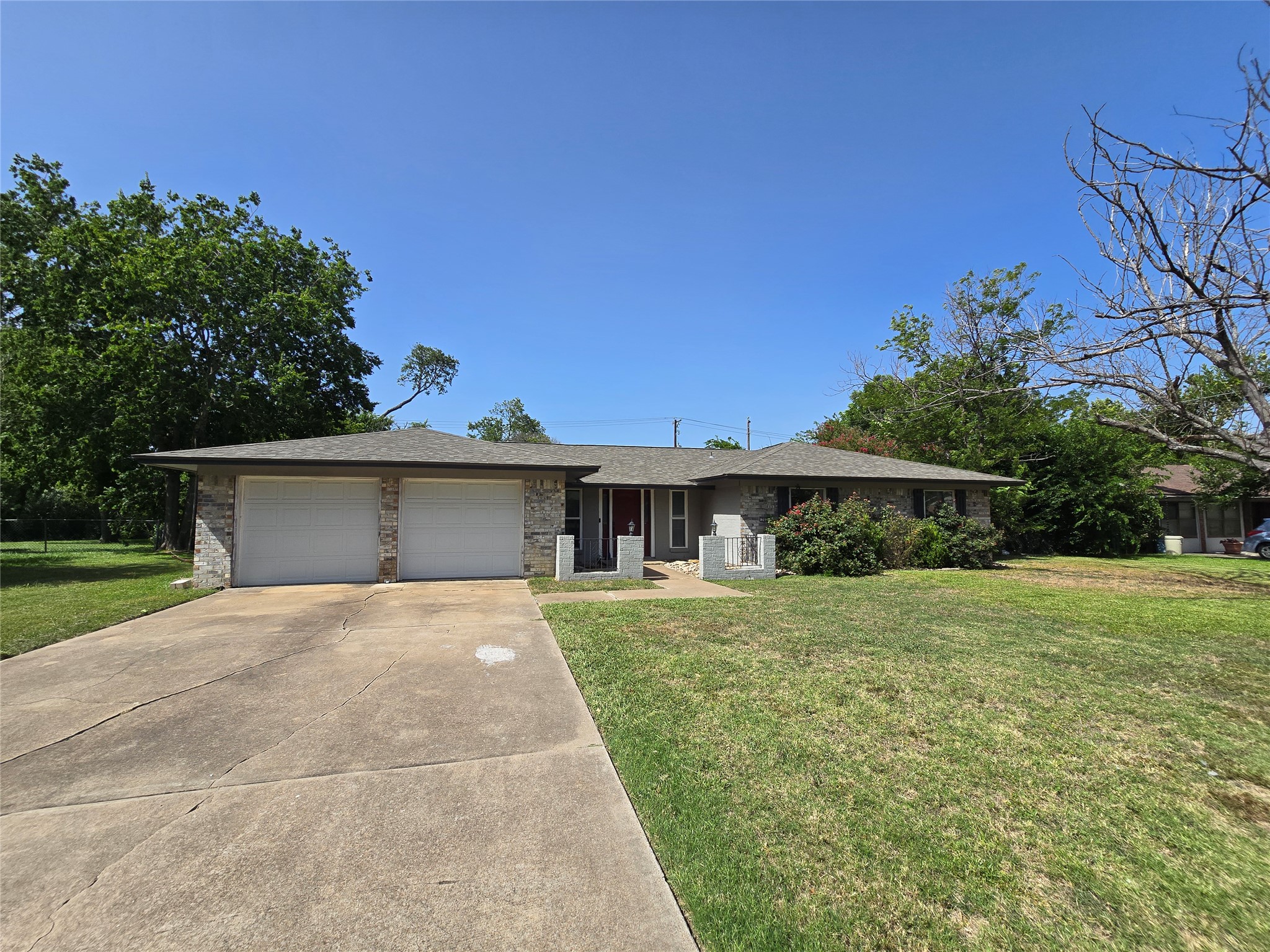 A classic brick exterior home with an attached two-car garage and a manicured lawn.