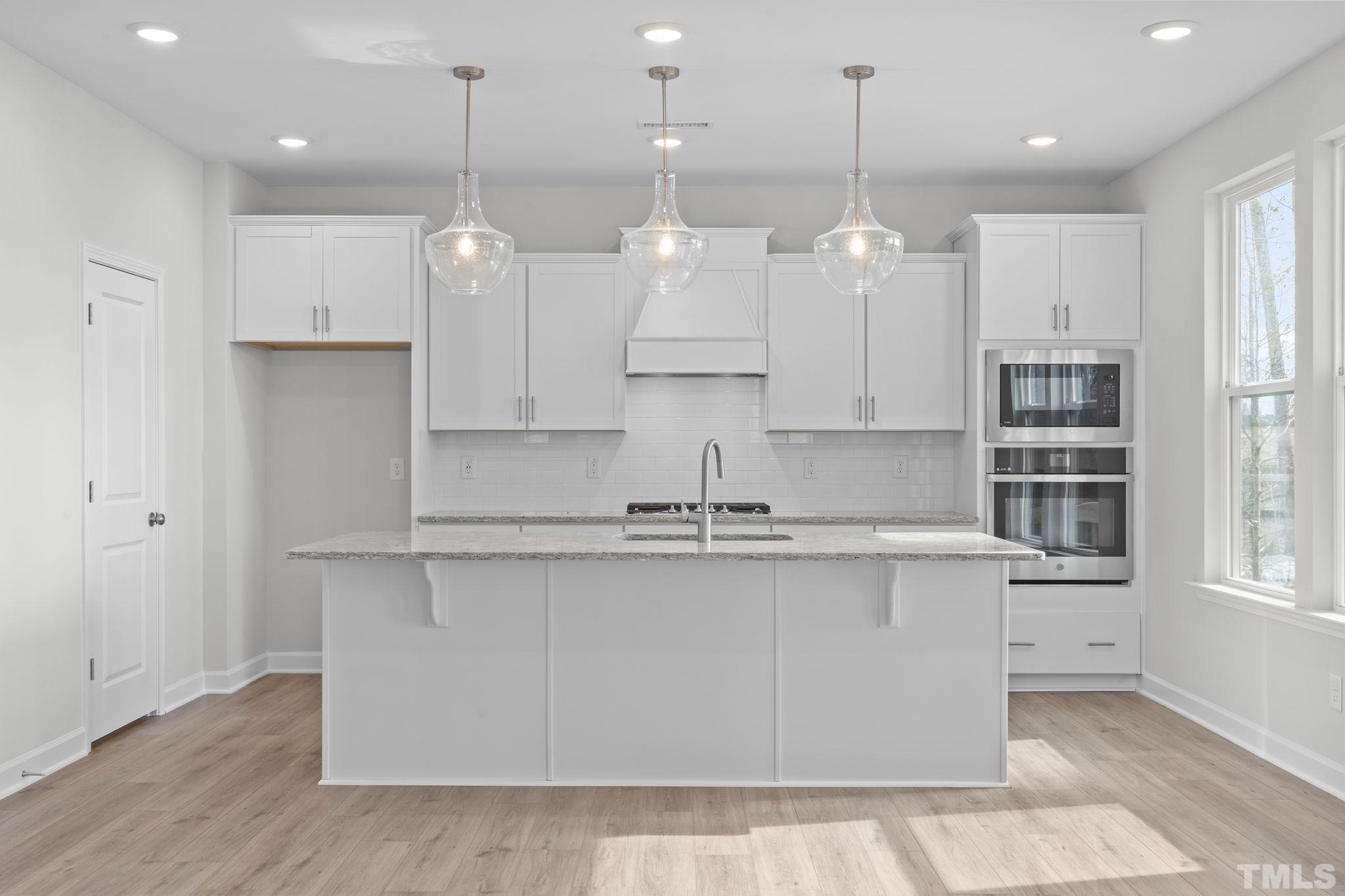 516 Craftsman Rdg Trail Knightdale, NC 27545 - Photo 6 of 45 a large kitchen with granite countertop a large kitchen island white cabinets and stainless steel appliances