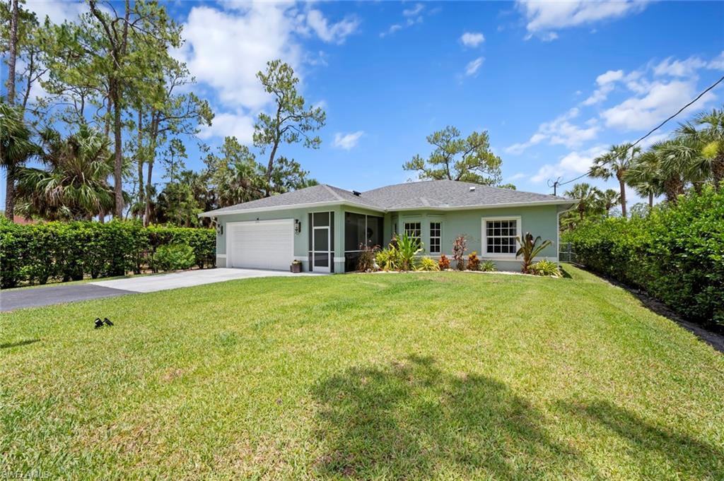 Single story home featuring driveway, a front yard, a garage, a sunroom, and stucco siding