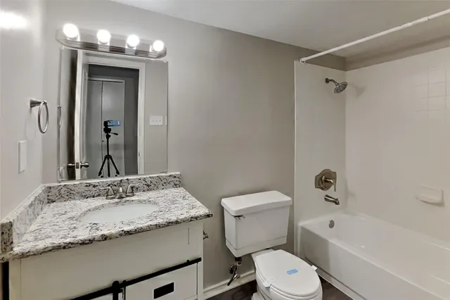 a bathroom with a granite countertop sink toilet a large mirror a bathtub and shower