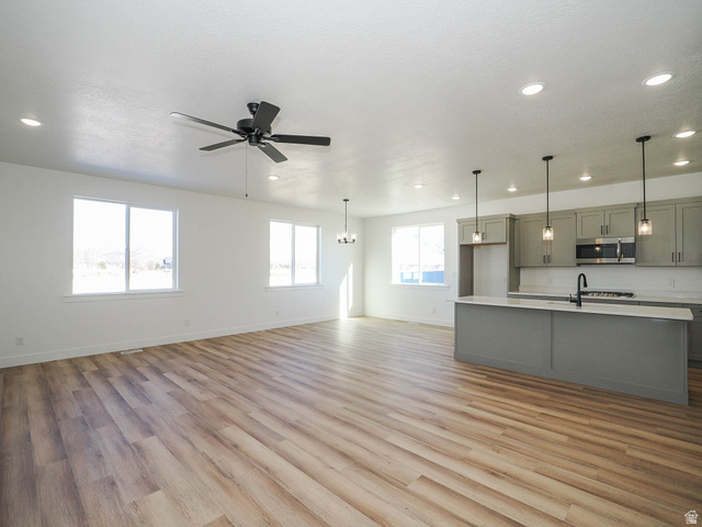 3938 North Wood Road Eagle Mountain, UT 84005 - Photo 10 of 55 Unfurnished living room featuring light wood-style floors, ceiling fan, and a chandelier