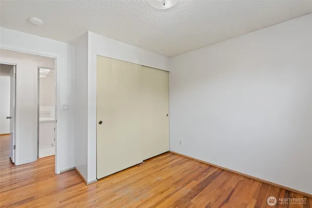 a view of an empty room with wooden floor and closet