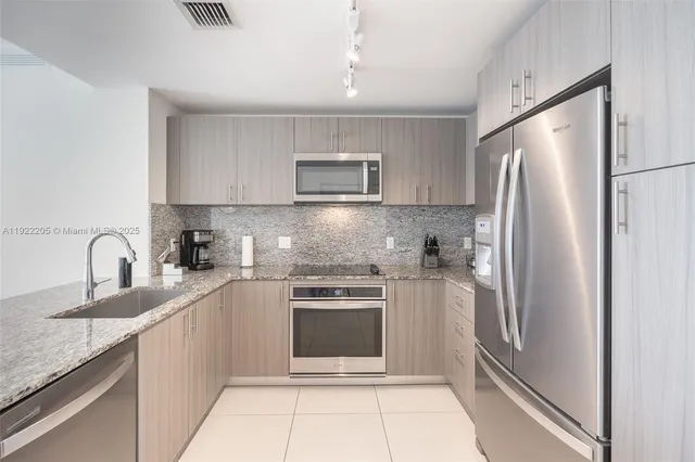 a kitchen with stainless steel appliances granite countertop a refrigerator sink and stove