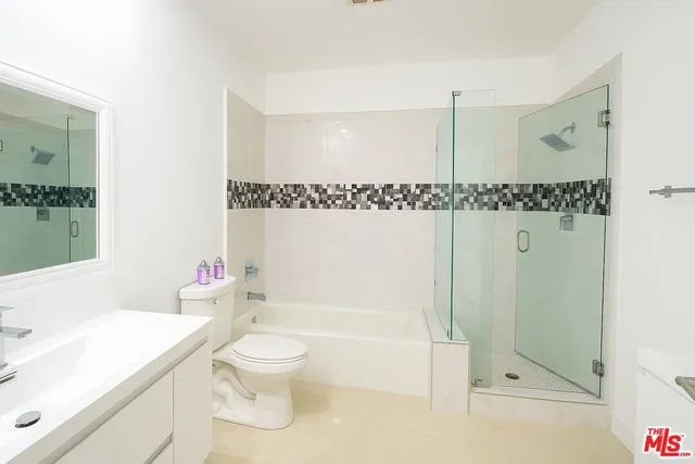 a bathroom with a granite countertop sink a toilet and shower