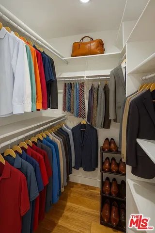 a view of walk in closet with clothes and shoes