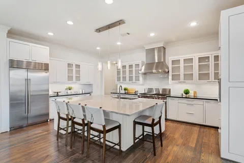 a kitchen with stainless steel appliances granite countertop a stove top oven a sink dishwasher and a refrigerator with wooden floor