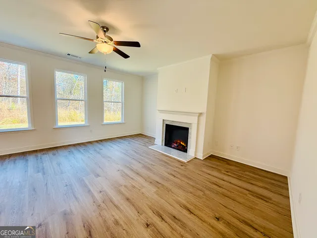 an empty room with wooden floor fireplace and windows