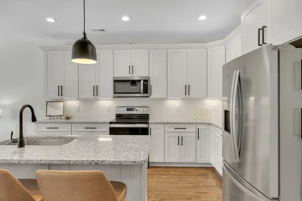 a kitchen with stainless steel appliances granite countertop a refrigerator a stove a sink a microwave and a refrigerator