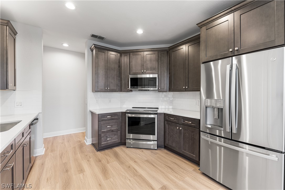 5080 Indigo Bay Boulevard, Unit 101 Estero, FL 33928 - Photo 8 of 33 a kitchen with stainless steel appliances a stove a sink and a refrigerator