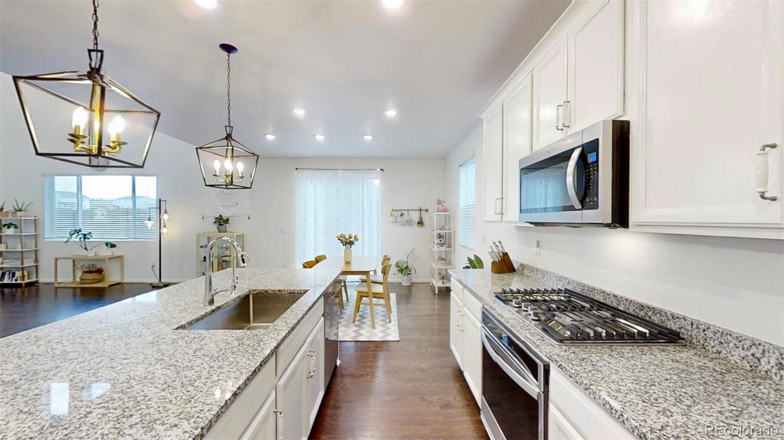 a kitchen with stainless steel appliances granite countertop a stove a sink a microwave oven and a counter space