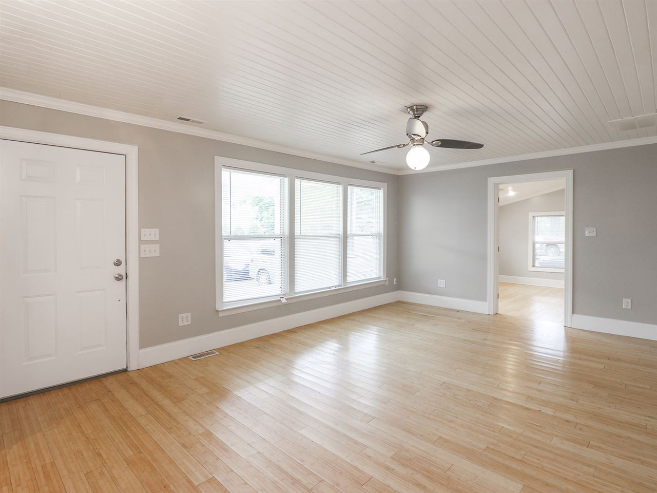 204 Proctor Street Zebulon, NC 27597 - Photo 16 of 30 an empty room with wooden floor chandelier fan and windows