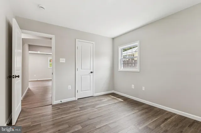 a view of an empty room with wooden floor and closet