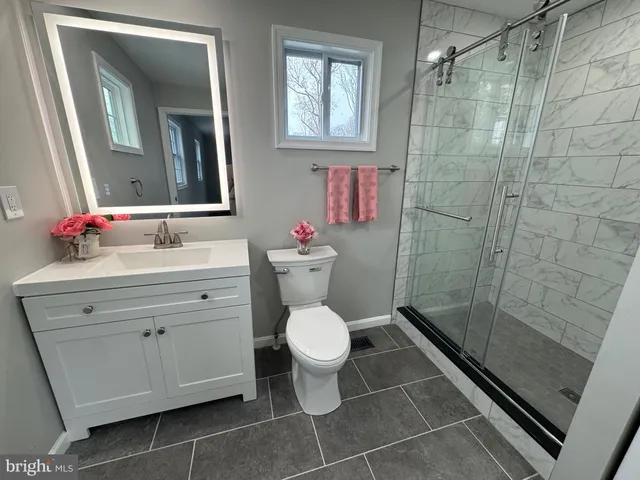 a bathroom with a granite countertop toilet sink and mirror