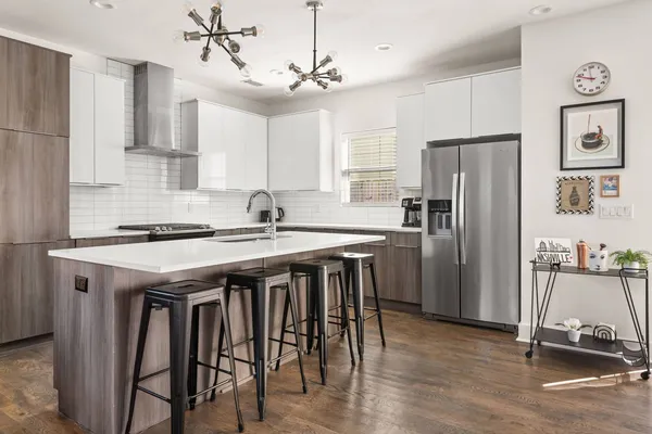 a kitchen with stainless steel appliances granite countertop a table chairs stove and refrigerator