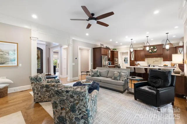 a living room with furniture kitchen view and a chandelier