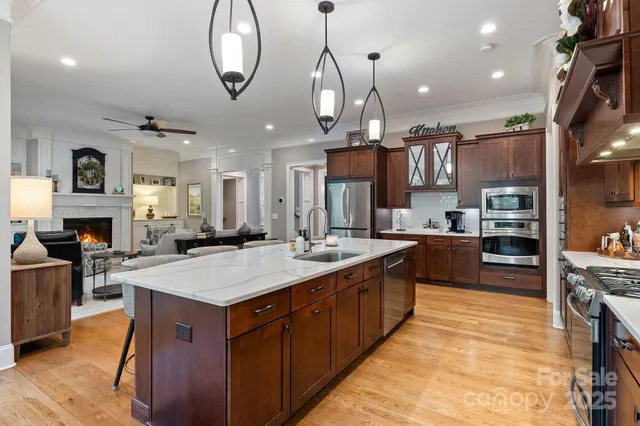 a large kitchen with stainless steel appliances a stove center island a oven a dining table and chairs