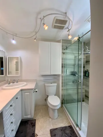 a kitchen with stainless steel appliances kitchen island granite countertop a refrigerator a stove top oven and couches with wooden floor