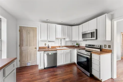 a kitchen with stainless steel appliances granite countertop a refrigerator a stove top oven a sink and dishwasher with wooden floor