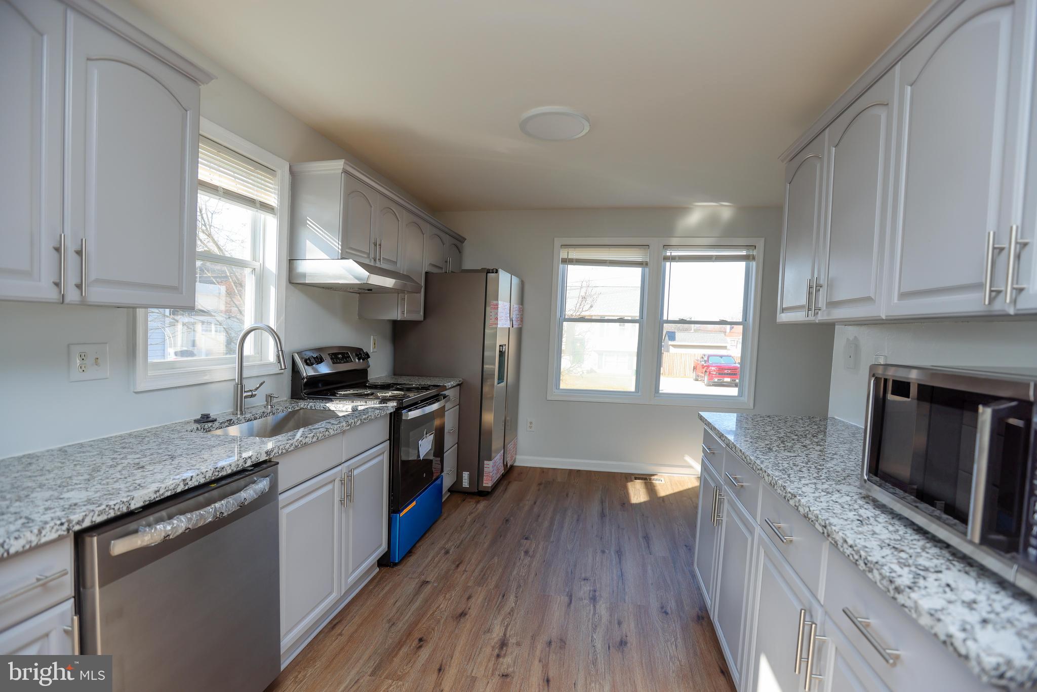 30 Queen Anne Road Glen Burnie, MD 21060 - Photo 11 of 47 a kitchen with granite countertop a stove a sink dishwasher and a microwave oven with wooden floor