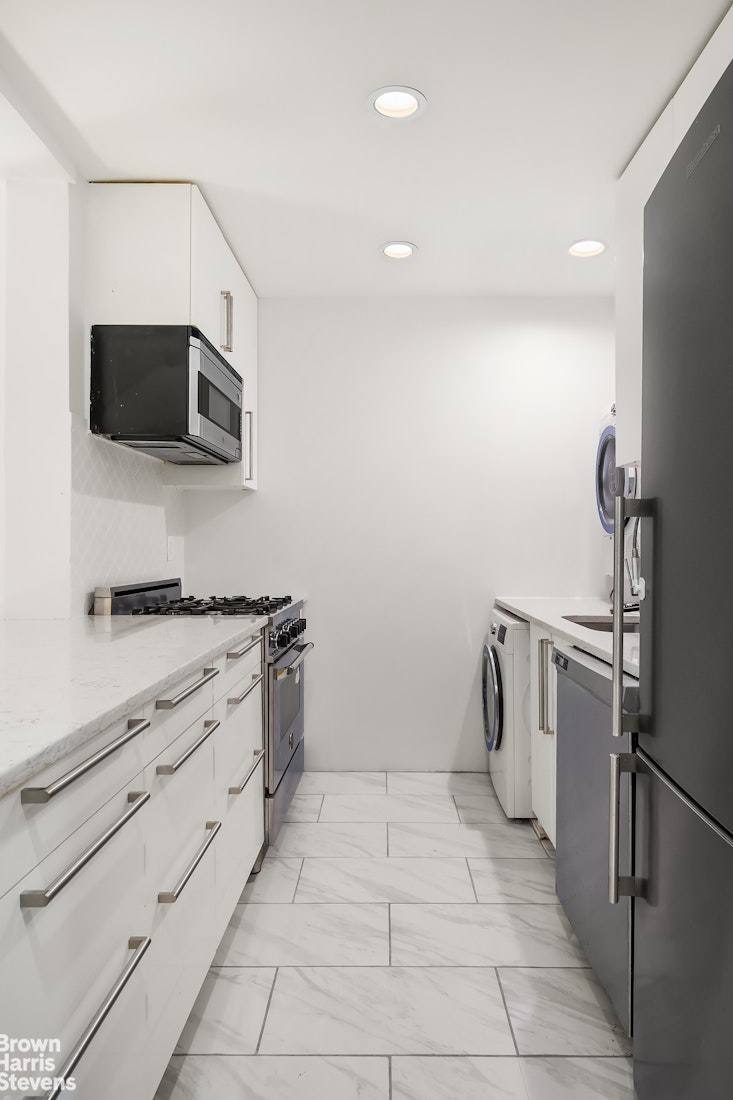 29 West 119th Street, Unit 3 Manhattan, NY 10026 - Photo 5 of 14 a kitchen with white cabinets and stainless steel appliances