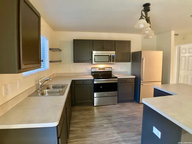 a kitchen with granite countertop a refrigerator stove and oven