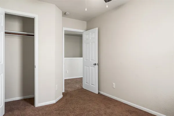 an empty room with a chandelier fan and a ceiling fan