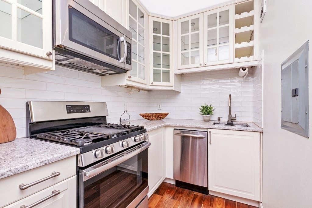 28 Juniper Street, Unit 79 Brookline, MA 02445 - Photo 5 of 23 a kitchen with stainless steel appliances granite countertop cabinets and a stove top oven