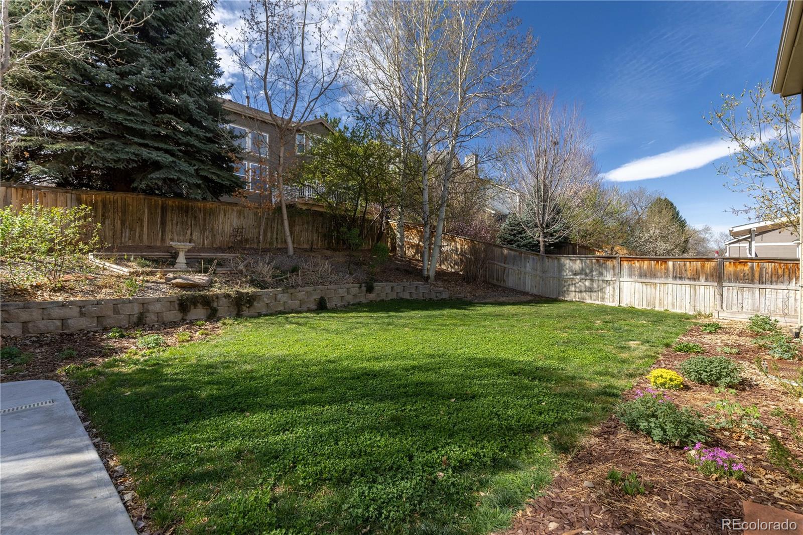 758 Huntington Place Highlands Ranch, CO 80126 - Photo 39 of 46 a backyard of a house with table and chairs plants and large trees