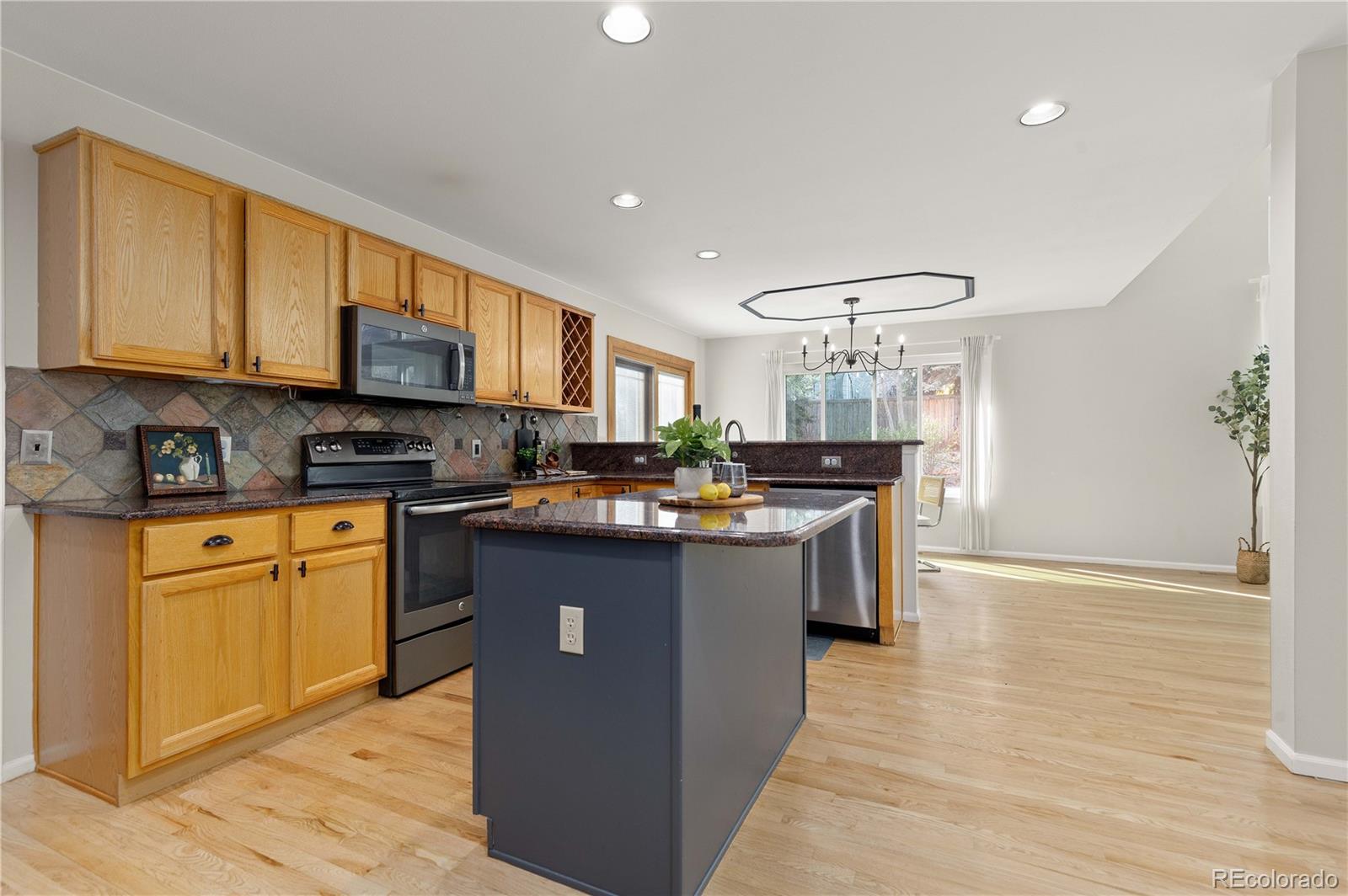 758 Huntington Place Highlands Ranch, CO 80126 - Photo 6 of 46 a kitchen with kitchen island granite countertop a sink cabinets and wooden floor