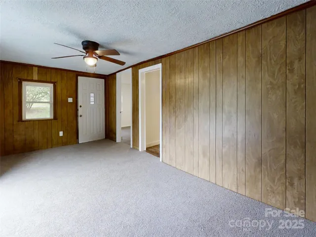 a view of an empty room with window and ceiling fan