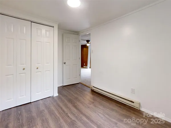 an empty room with wooden floor and mirror