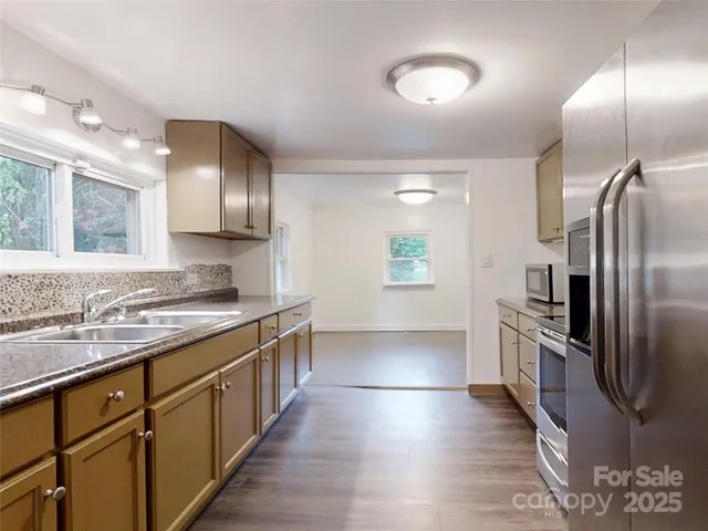 a kitchen with stainless steel appliances granite countertop a sink a stove and a refrigerator