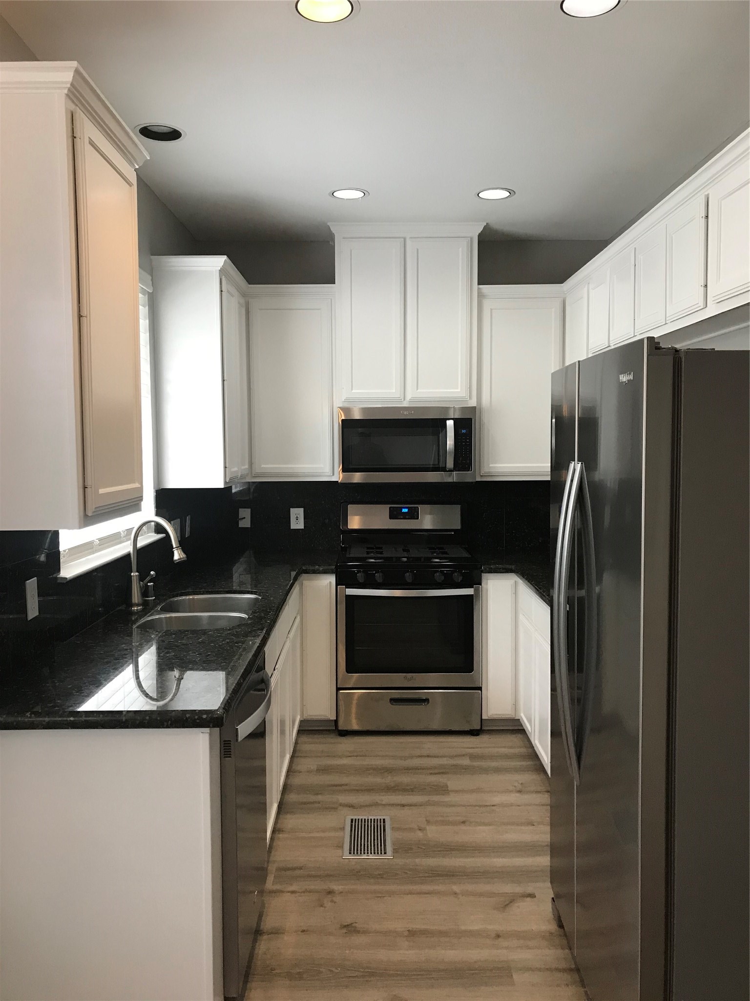 a kitchen with granite countertop a refrigerator sink and stove