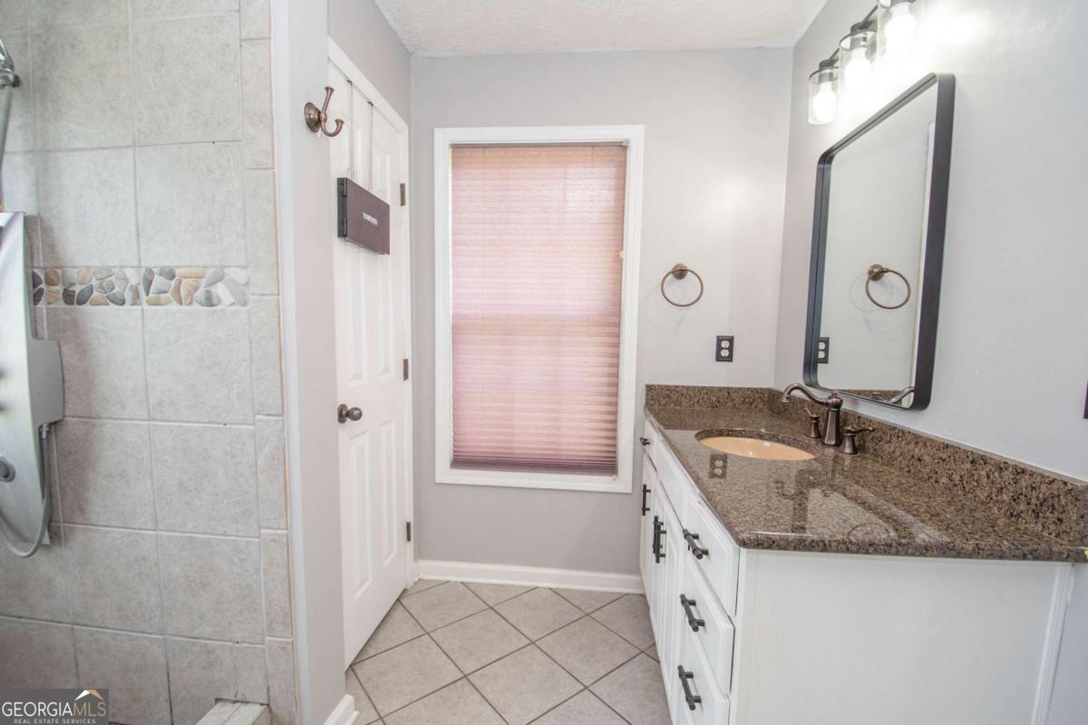 737 John Lovelace Road LaGrange, GA 30241 - Photo 17 of 46 a bathroom with a granite countertop sink a mirror and a bathtub