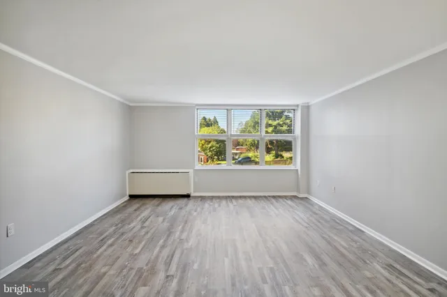 an empty room with wooden floor and window