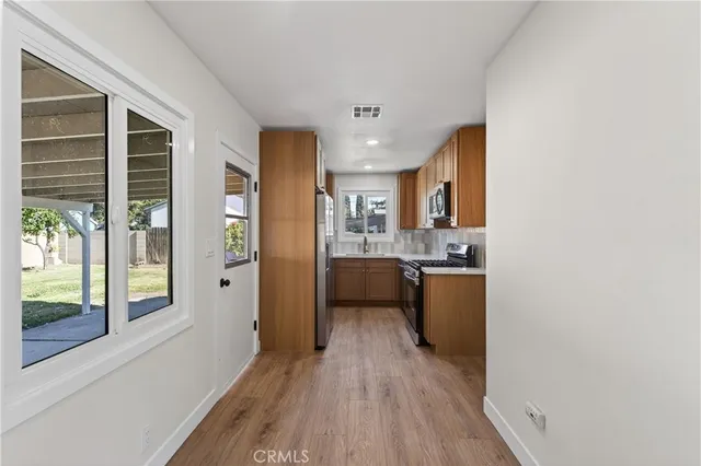 a kitchen with stainless steel appliances granite countertop a refrigerator a sink dishwasher a stove and white countertops with wooden floor