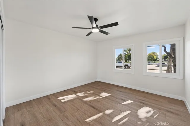 a view of empty room with wooden floor and ceiling fan