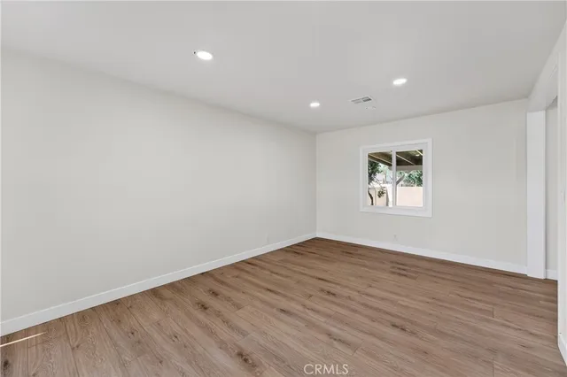an empty room with wooden floor and window