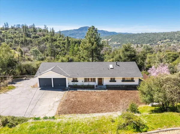 a aerial view of a house with a yard and trees in the background