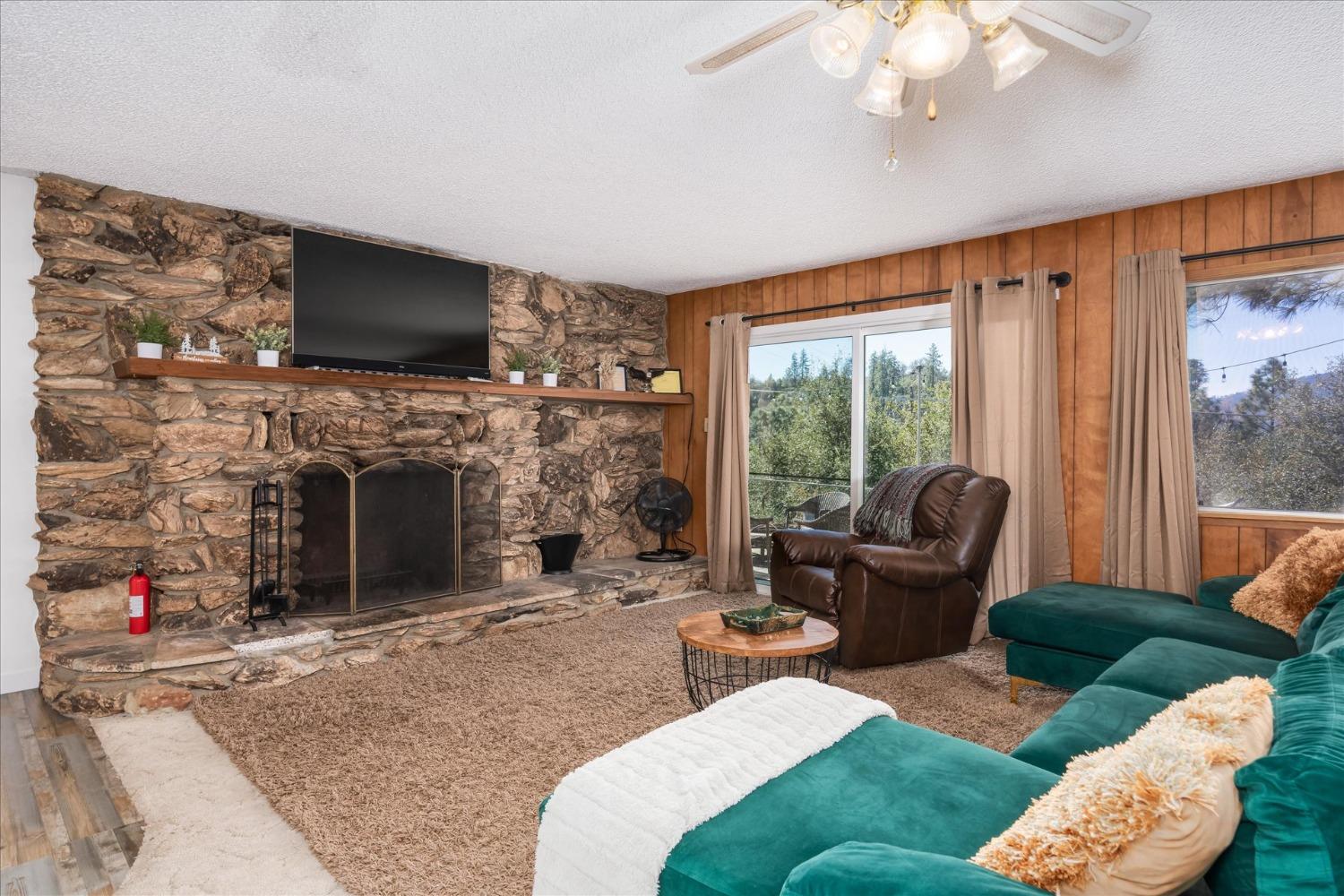42324 Buckeye Road Oakhurst, CA 93644 - Photo 10 of 45 a living room with furniture a flat screen tv and a fireplace