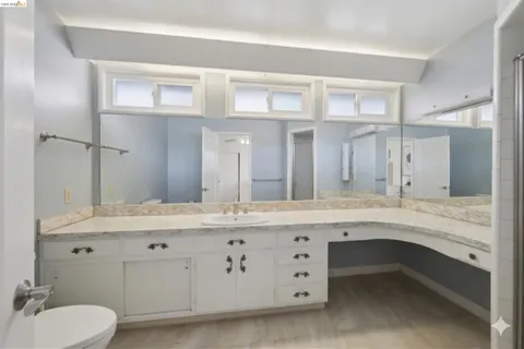a bathroom with a granite countertop sink mirror and toilet