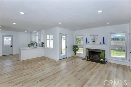 a view of an empty room with wooden floor and a fireplace