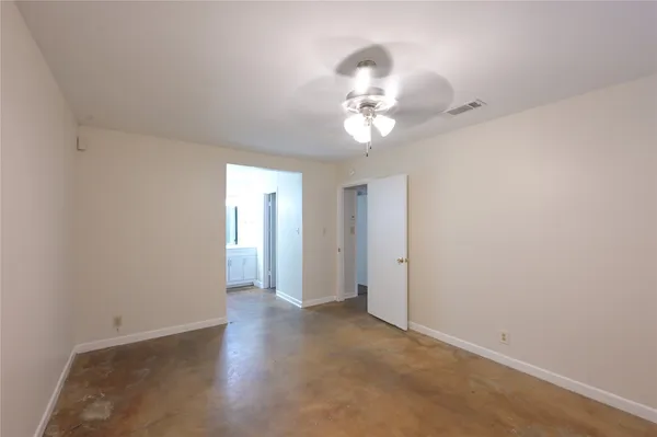 an empty room with a chandelier fan and wooden floor