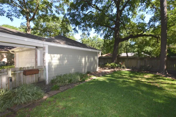 a view of a backyard with table and chairs and potted plants with large tree