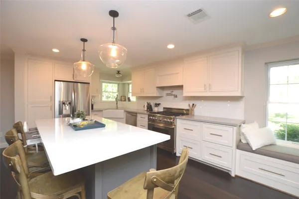 a kitchen with stainless steel appliances kitchen island granite countertop a table chairs and a stove